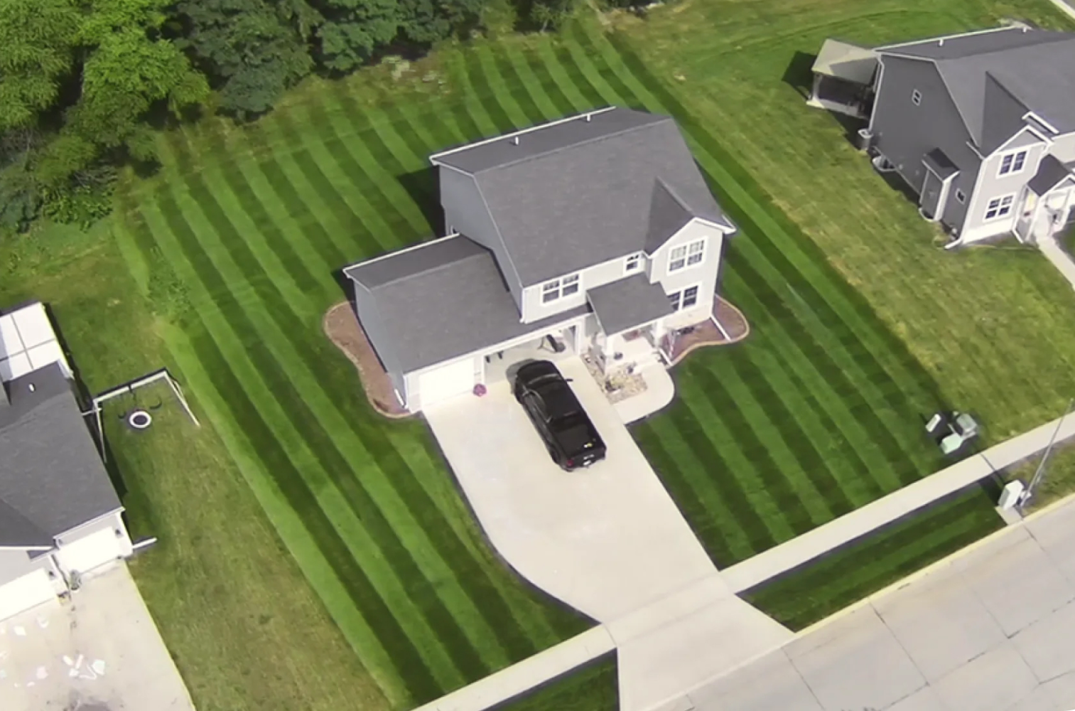 Aerial view of a house with the greenest and best trimmed lawn in the neighborhood.